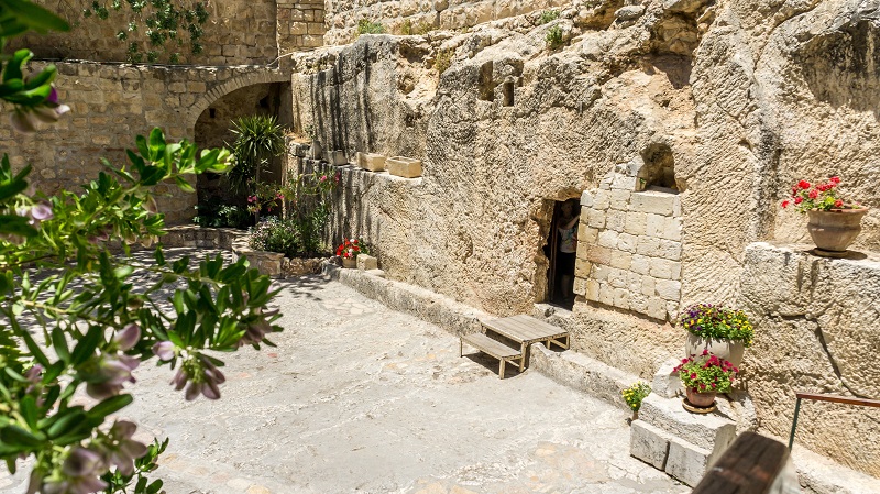 Trdgrdsgraven i Jerusalem, ingngen till denna grav uthuggen ur klippan r ngon meter hg, runtom str ngra krukor med blommor. 